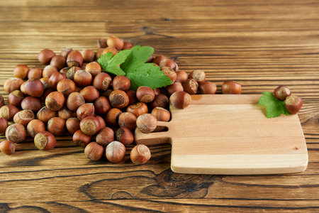 Hazelnut on a wooden background with leaves and a cutting board.の写真素材