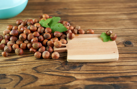 Hazelnuts on a wooden background with a wooden cutting board.の写真素材