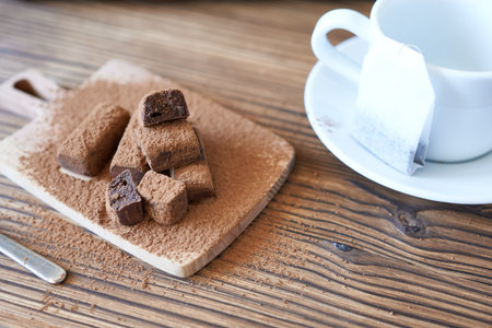 A cup and saucer and a tea bag with candy sprinkled with cocoa. A sweet snack, a time of pause.の写真素材