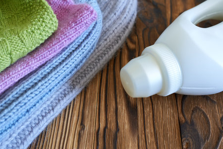 Bottle of detergent and knitted sweaters on wooden backgroundの写真素材