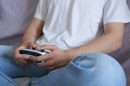 Close-up of man playing video game on sofa in living room