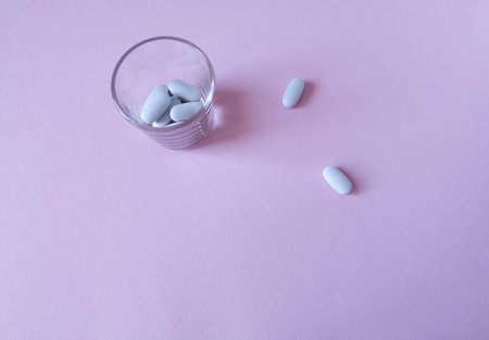 White pills in a glass on a pink background. copyspace.の写真素材