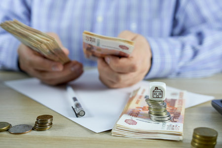 A man counting money on a table and saving it to buy a house.の写真素材