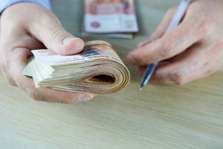 Man counting money on wooden table, closeup of hands counting money