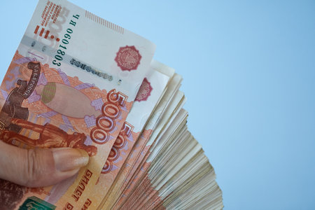 Banknotes of Russian rubles in the hand of a woman on a blue background close-up.