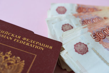 Russian passport and banknotes on pink background. Selective focus.