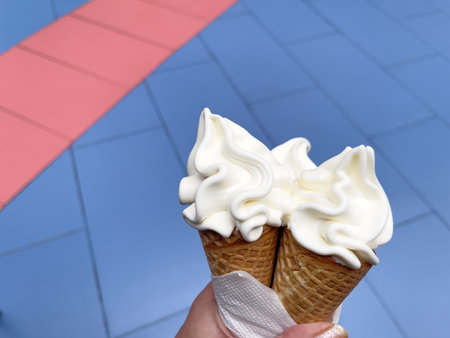 ice cream cone in hand on the background of a blue tile wall
