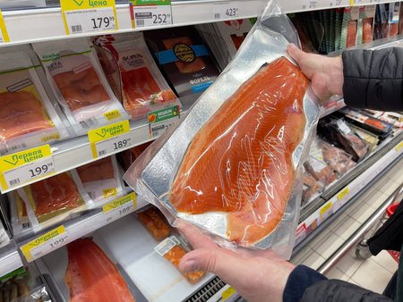Novosibirsk, Siberia, Russia - November 11, 2023. A man buys salmon in a supermarket. Selective focus on fish. Supermarket, Auchanのeditorial素材