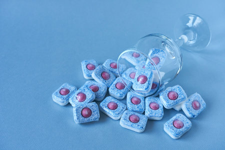 Dishwasher detergent with wine glass on blue background. Place for copying.