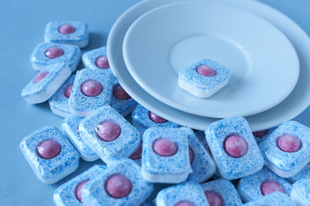 Dishwasher detergent in tablet form against clean dishes. Shallow focus.の写真素材