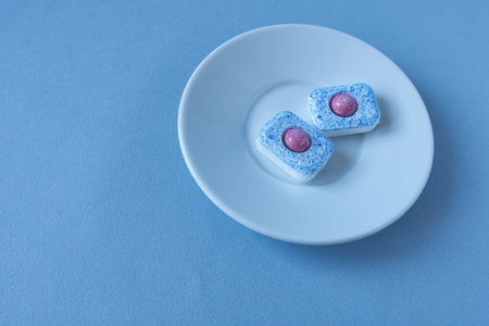 White plate with dishwasher tablets on blue background.の写真素材