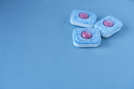 Close-up of blue and pink dishwasher tablets on blue background with copy space.の写真素材