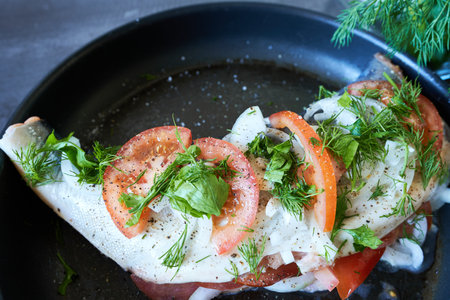 Raw fish with tomatoes and dill in a pan on a dark background. Cooking fish.