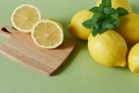 Lemons, mint and cutting board on a green background.の写真素材
