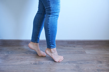 Female legs in jeans on a wooden floor, close-up.