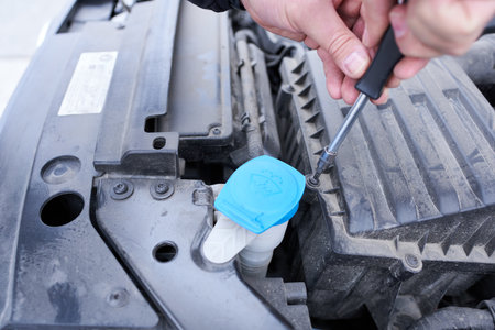 Changing the air filter in a car. Close-up of a man tightening a bolt while assembling parts. Car...