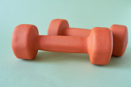 Two orange dumbbells on a green background. Fitness concept.の写真素材