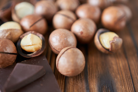 Macadamia nuts and chocolate on a wooden table, close-up. Soft focus.の写真素材