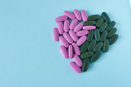 Pink and green tablets on a blue background with space for text. Vitamins for women and men.