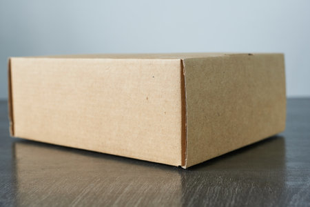 Cardboard box on wooden table, close-up. Space for text