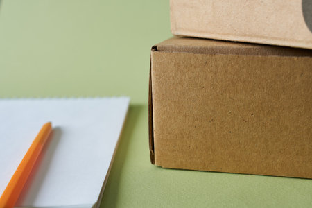 Brown cardboard box and pencil on green background with copy space for textの写真素材