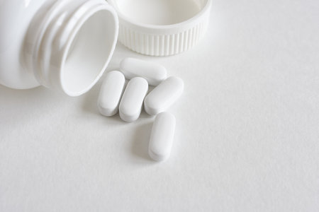 White pills on a white background with copy space. Focus on foreground.