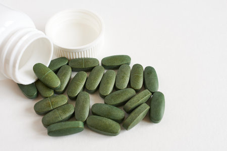 Green pills on white background with copy space. Focus on foreground.