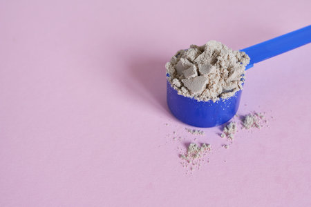 Blue scoop with whey protein powder on pink background. Copy space.の写真素材