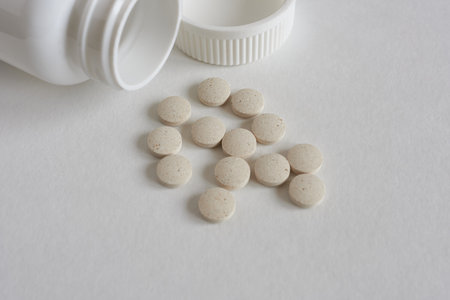 Pills spilling out of pill bottle on white background. Focus on foreground.の写真素材