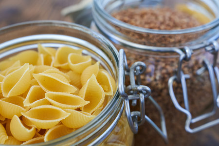 raw pasta in a glass jar on a wooden table close-upの写真素材