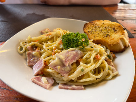 Spaghetti carbonara with bacon and toasted baguette.の写真素材