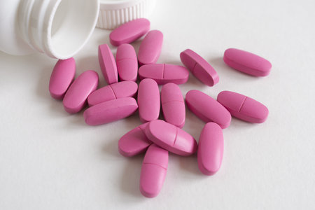 pink pills and bottle on white background. Focus on foreground, soft bokeh.の写真素材