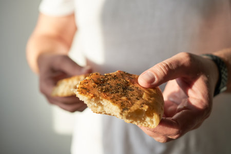 Bread in hands of a man on a gray background. Selective focus.