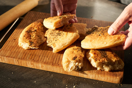 Freshly baked buns with spices on a wooden cutting board in the hands of a man.