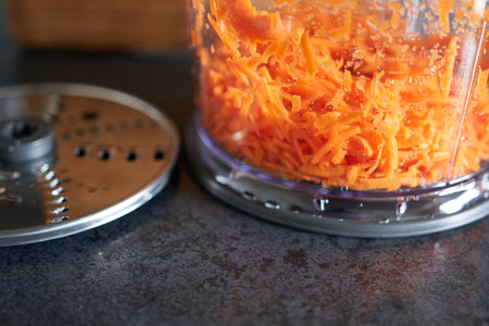 A food processor with grated carrots on the table. Close-up.の写真素材