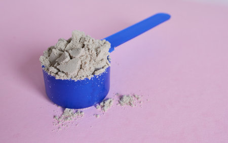 A scoop of whey protein powder on a pink background. Chocolate protein.の写真素材