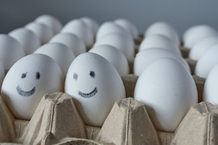 Eggs with smiley faces in carton box on gray backgroundの写真素材