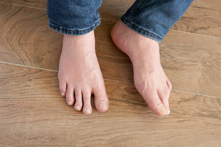 Close-up of a man's bare feet on a wooden floor.の写真素材
