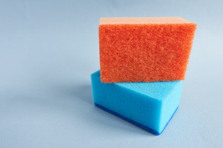 Colorful sponges for washing dishes on a blue background.