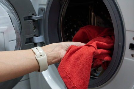 Washing machine with a red cloth and hand of woman doing laundryの写真素材