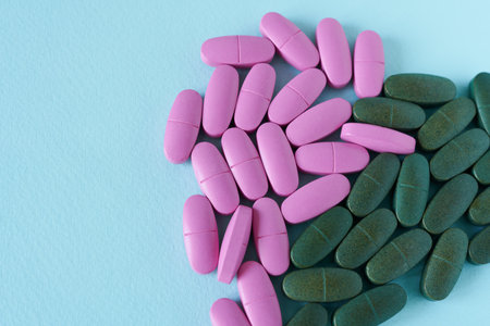 Pink and green pills on blue background. Copy space for text.
