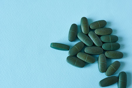 Green pills on a blue background. Top view with copy space.の写真素材