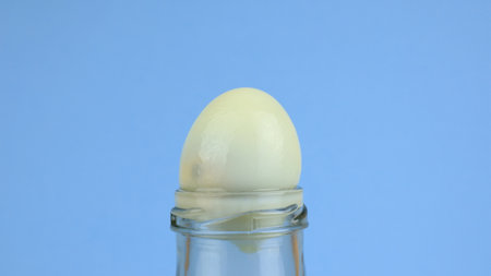 Put the eggs in the bottle. Egg and glass bottle trick on blue background