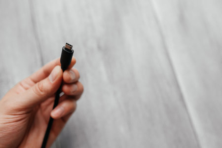 man holds usb type c cable on white wooden background. The newest and fastest device connection...