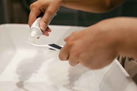 beautiful caucasian woman in the bathroom squeezes out toothpaste on the toothbrush. Close shot of...