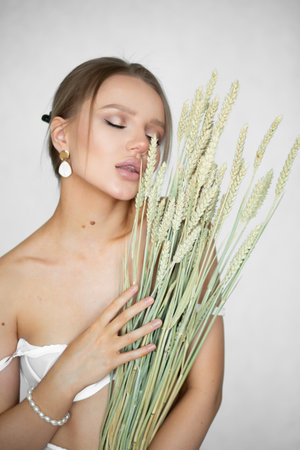 Beautiful woman in underwear with ears of wheat in hands on a white background.の写真素材