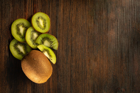 kiwi and chopped pieces of kiwi on a dark wooden background top viewの写真素材