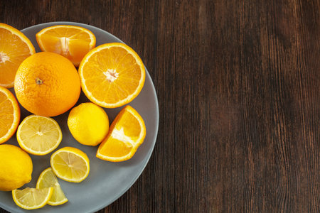 Lemons and oranges on a plate on a dark wooden backgroundの写真素材