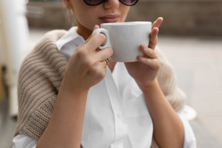 Beautiful girl in a street cafe drinks coffeeの写真素材