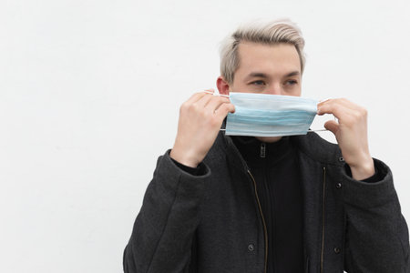 Man putting on a medical mask on a white background in the street